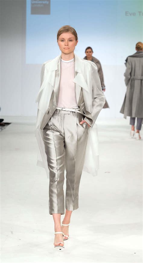 A Model Walks Down The Runway In Silver Pants And White Top While
