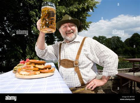 A Traditionally Clothed German Man In A Beer Garden Raising His Beer