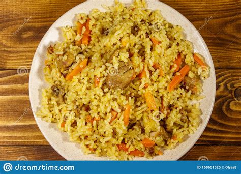 Pilaf With Meat Rice Carrot And Onion In Plate On Wooden Table Top