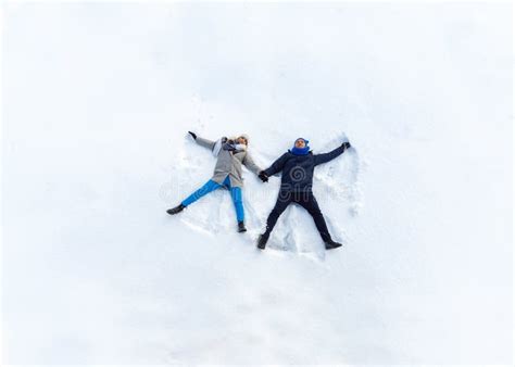 Happy Young Couple In Winter Park Lying On Snow Making Snow Angel Top