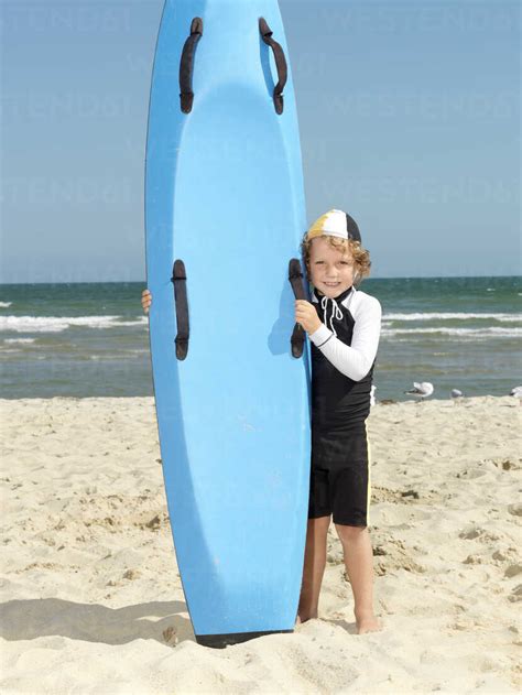Portrait Of Cute Boy Nipper Child Surf Life Savers Next To Surfboard