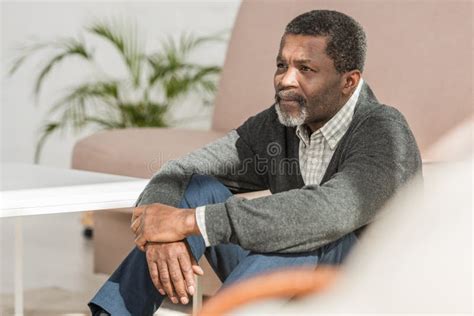 Depressed African American Man Sitting On Floor At Home And Looking