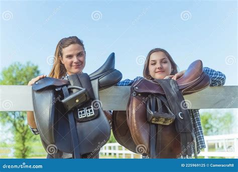 Two Young Girls In The Horse Ranch Leather Saddles Hanging On The