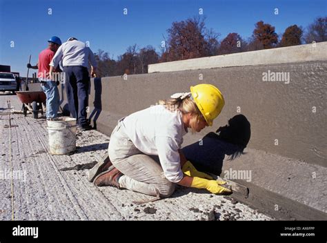 Female Construction Worker Smoothing Wet Concrete On New Interstate