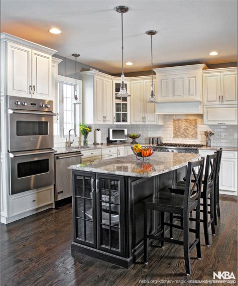 White kitchen cabinets with a dark grey island omega. Ebony black island surrounds by Antique white cabinets - NKBA