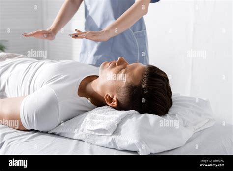 Partial View Of Healer Standing Near Man On Massage Table And Holding