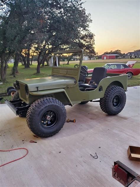 An Old Green Jeep Is Parked In The Driveway