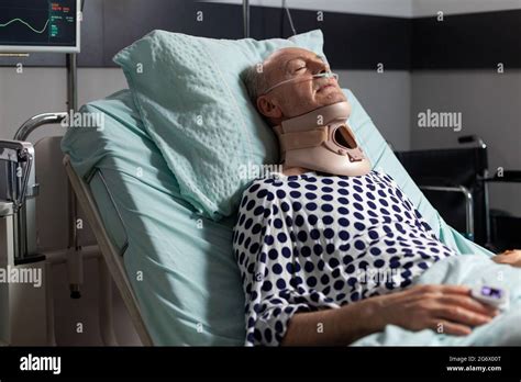 Elderly Man Laying In Hospital Room Bed Wearing Cerival Collar With Iv