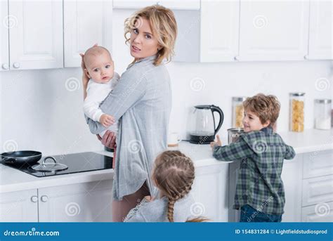Tired Mother Holding Infant Child And Looking At Camera While Naughty