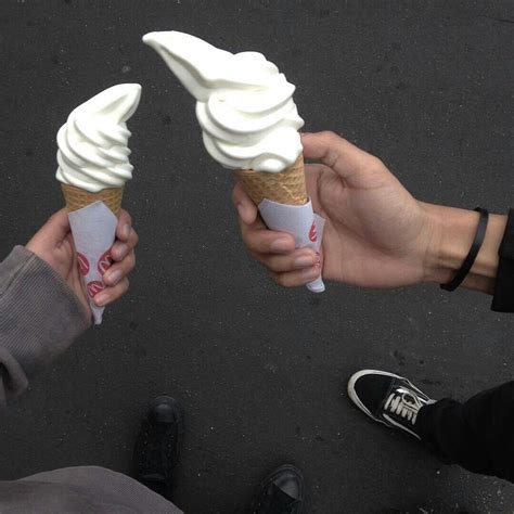 Two People Holding Ice Cream Cones In Their Hands
