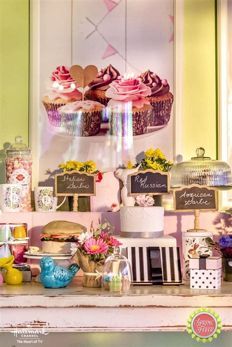 A Table Topped With Lots Of Cakes And Cupcakes Next To A Wall Mounted Sign