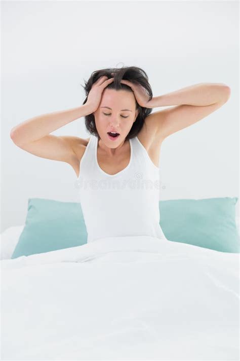 Sleepy Woman Yawning While Stretching Her Arms In Bed Stock Image