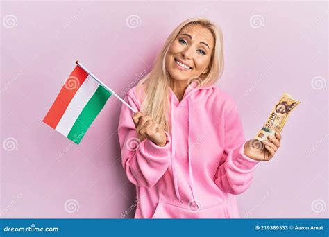 Young Blonde Woman Holding Hungary Flag And Forint Banknotes Celebrating Crazy And Amazed For
