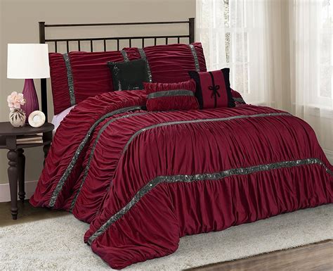 A Bed With Red Comforter And Pillows In A Room