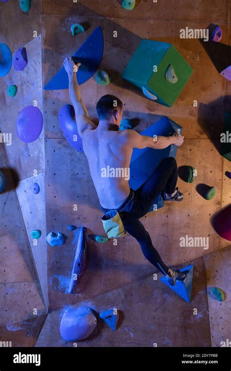 Back View Of Shirtless Muscular Man Climbing Wall Without Belay During