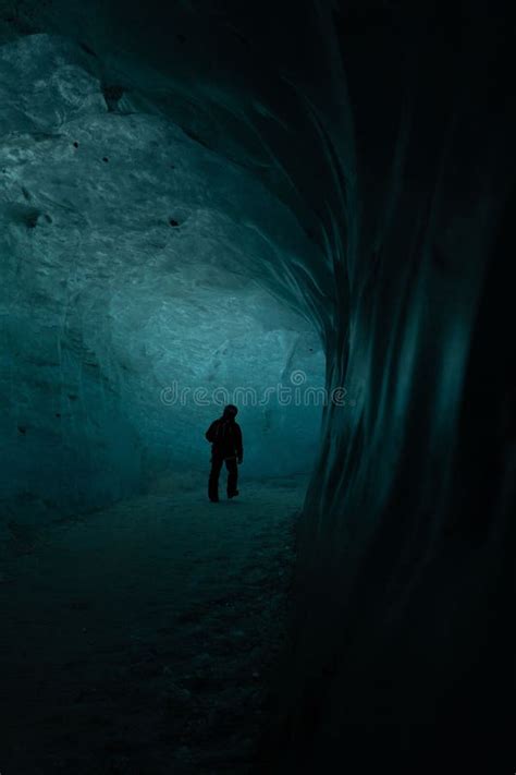 Man Stands In An Awe Inspiring And Mysterious Dark Ice Cave Illuminated