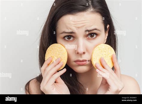 Attractive Brunette With Bare Shoulders Holds Sponges Near Her Face