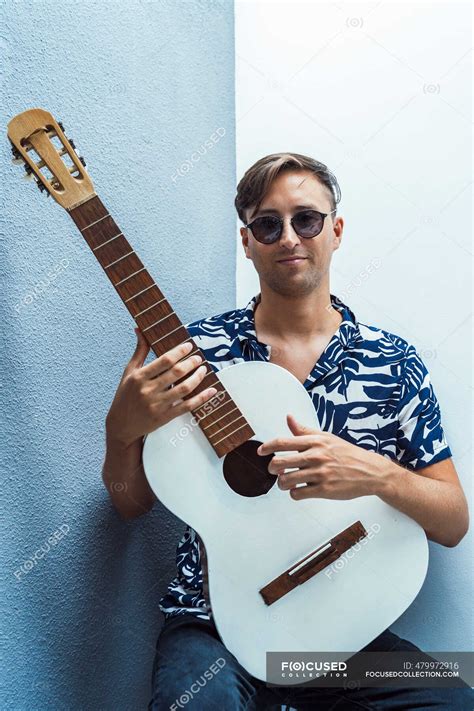 Smiling Musician Holding Guitar Against Blue Wall — People String
