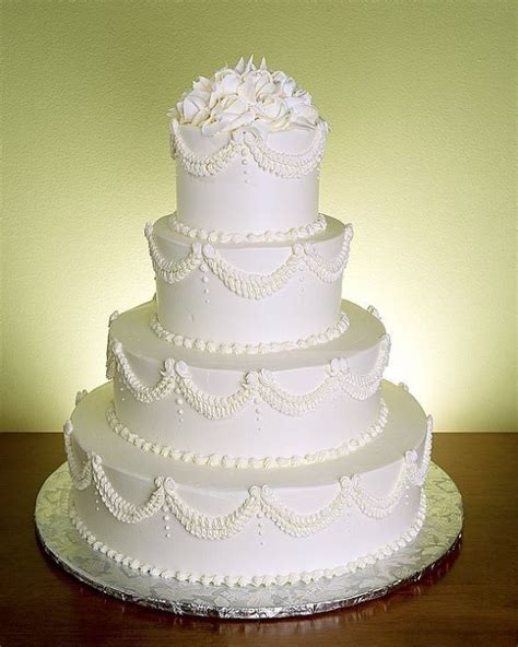a three tiered white wedding cake sitting on top of a table