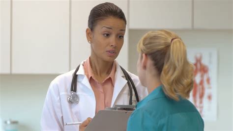 A Young Hispanic Male Doctor And His Physicians Assistant Talk To A