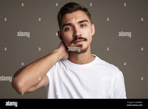 Image Of Caucasian Handsome Guy Rubbing His Neck While Posing On Camera Isolated Over Grey
