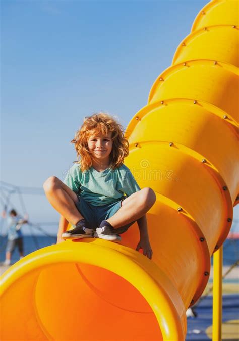 Child On Slide Playground Area Cute Boy In The Kids Park Having Fun