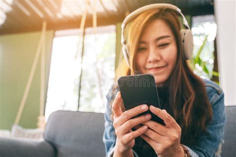 A Woman Using Mobile Phone And Headphone To Listen To Music Stock Image