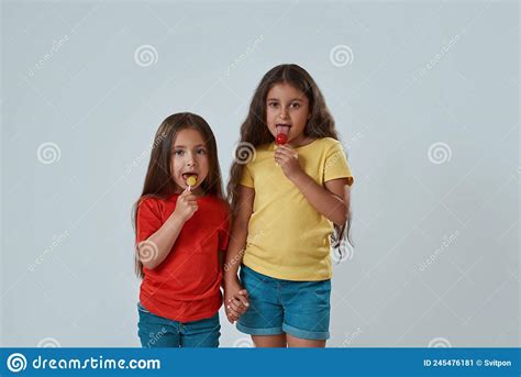 two girls licking lollipops and looking at camera stock image image of people friends 245476181