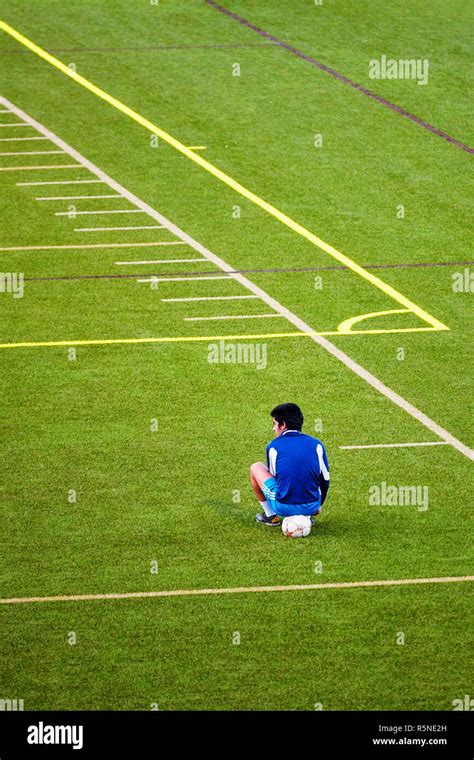 Unhappy Teenage Boy Excluded From The Soccer Team Sits On The Ball At