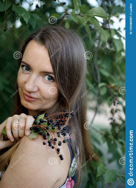 a beautiful mature woman with long hair collects cherry berries from a tree everyday life of a