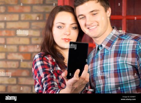 Young Couple Posing For A Selfie Standing Close Together Smiling Into Their Mobile Phone Camera