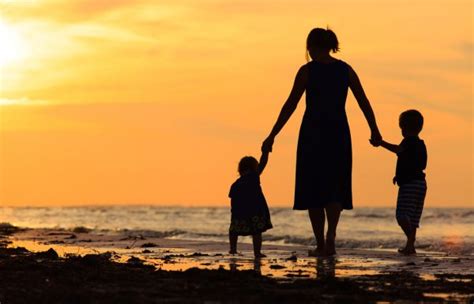 Madre Y Dos Niños Caminando En La Playa Al Atardecer Fotografía De