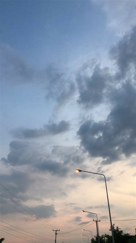 The Sky Is Very Cloudy And There Are Street Lights In The Foreground