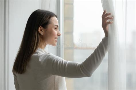 Close Up Happy Young Woman Opening Curtains Looking Out Window Stock