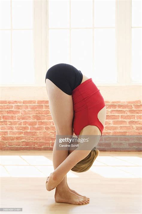 Young Woman Bending Over In Yoga Pose Arms Around Legs Side View High
