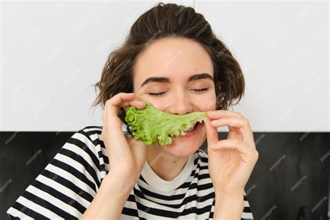 サラダの葉でポーズをとる野菜を食べることを好きな若い女性ベジタリアンの肖像画 無料の写真