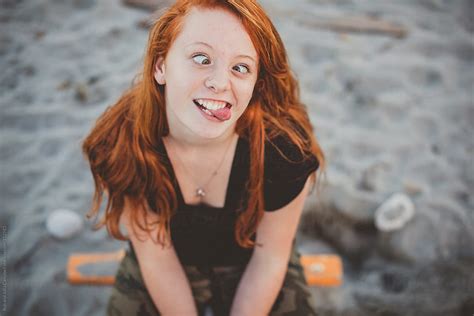 Portrait Of Redhead Teenage Girl Sitting At The Beach Being Goof By