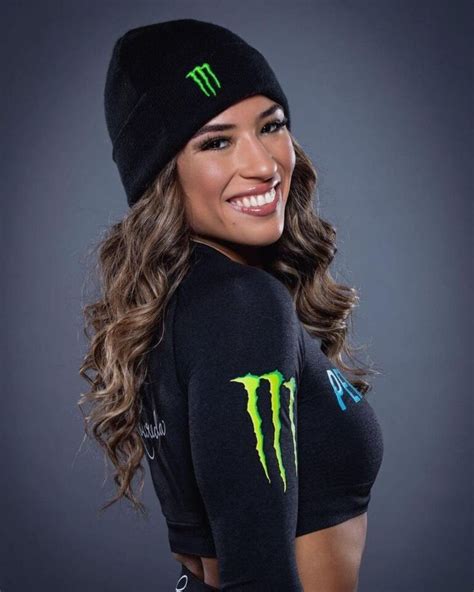 A Woman With Long Hair Wearing A Black Top And Green Monster Logo On
