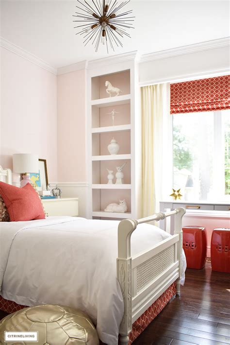 A floor bed lighted by a pair of industrial pendants along with a wooden side table and a fuchsia pink bean bag filled this primary bedroom. BLUSH PINK AND CORAL BEDROOM WITH BRASS ACCENTS