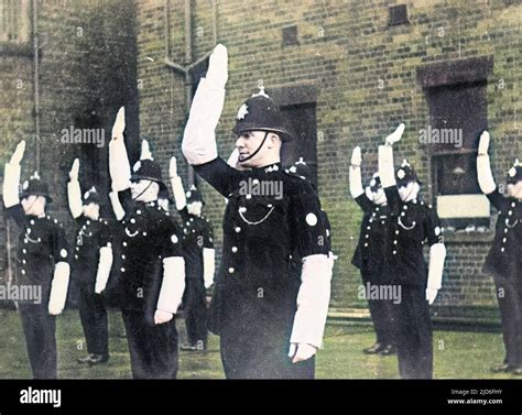 a group of british traffic policeman learning hand signals in a training yard colourised