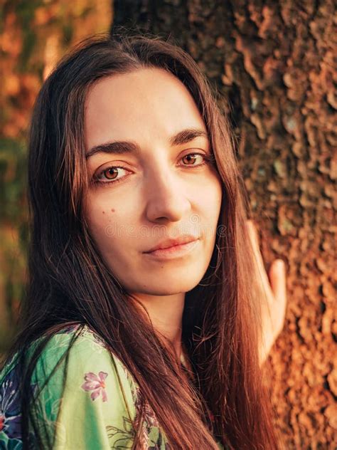 Portrait Beautiful Caucasian Brunette Girl With Long Hair In The Forest At Sunset Leaned Against