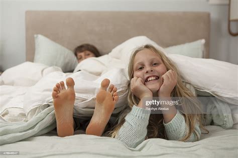 portrait of girl lying on bed with mothers feet photo getty images
