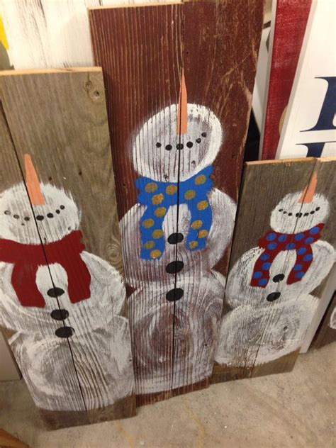 Three Snowmen Are Painted On Wood Boards