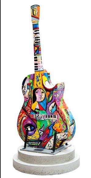 A Colorful Guitar Sculpture Sitting On Top Of A White Pedestal