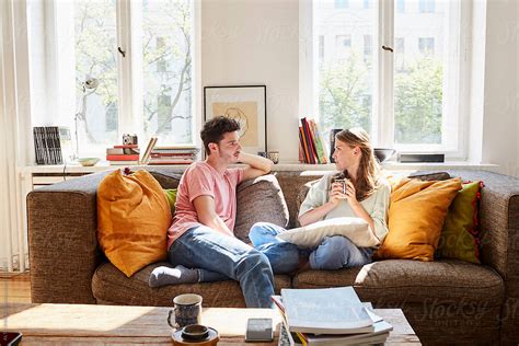 Young Couple Talking While Sitting On Sofa At Home By Stocksy Contributor Alto Images Stocksy
