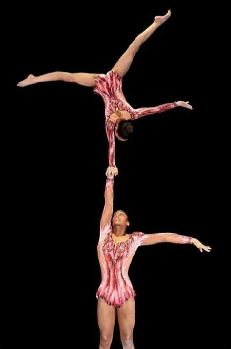 Two People Are Doing Acrobatic Tricks In The Air With Their Hands Together