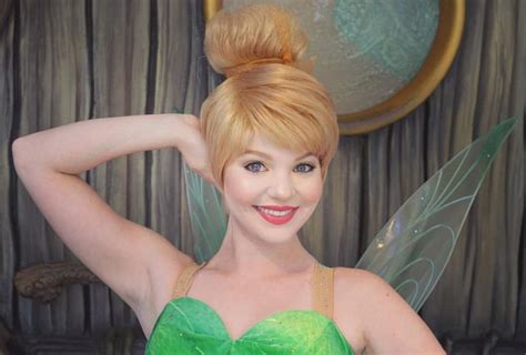 A Woman Dressed As Tinkerbell Posing For The Camera With Her Hands Behind Her Head