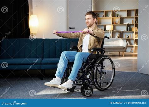 Young Disabled Man In Wheelchair Doing Exercises With Rubber Band At