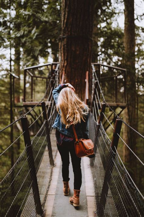 a woman walking across a suspension bridge in the woods