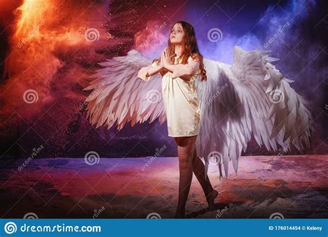 White Angel On A Dark Background With Colored Lighting The Concept Of